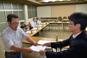 写真：菅野副町長が「収穫祭」実行委員会代表の新妻良平さんに委嘱状を手渡す様子