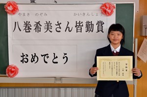 写真：八巻希美さんに小学校6年間の皆勤賞が授与されている様子