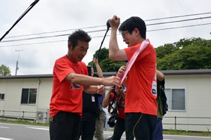写真：KANPEIみちのくマラソンで間寛平さんが福島中央テレビの徳光雅英アナウンサーにタスキを託している様子