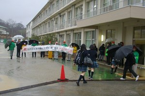 写真：3月1日横断幕を持って卒業生の登校を迎える様子