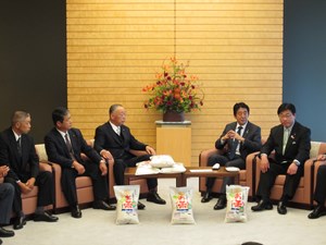 写真：山田基星町長が首相官邸を訪れて新米を贈呈する目録を渡している様子